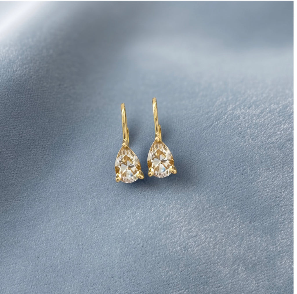 Violet Pear Earrings with champagne stones and gold-tone lever backs on a blue-grey surface.