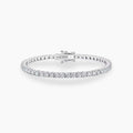 Silver tennis bracelet with round stones and a box clasp, shown against a white background.