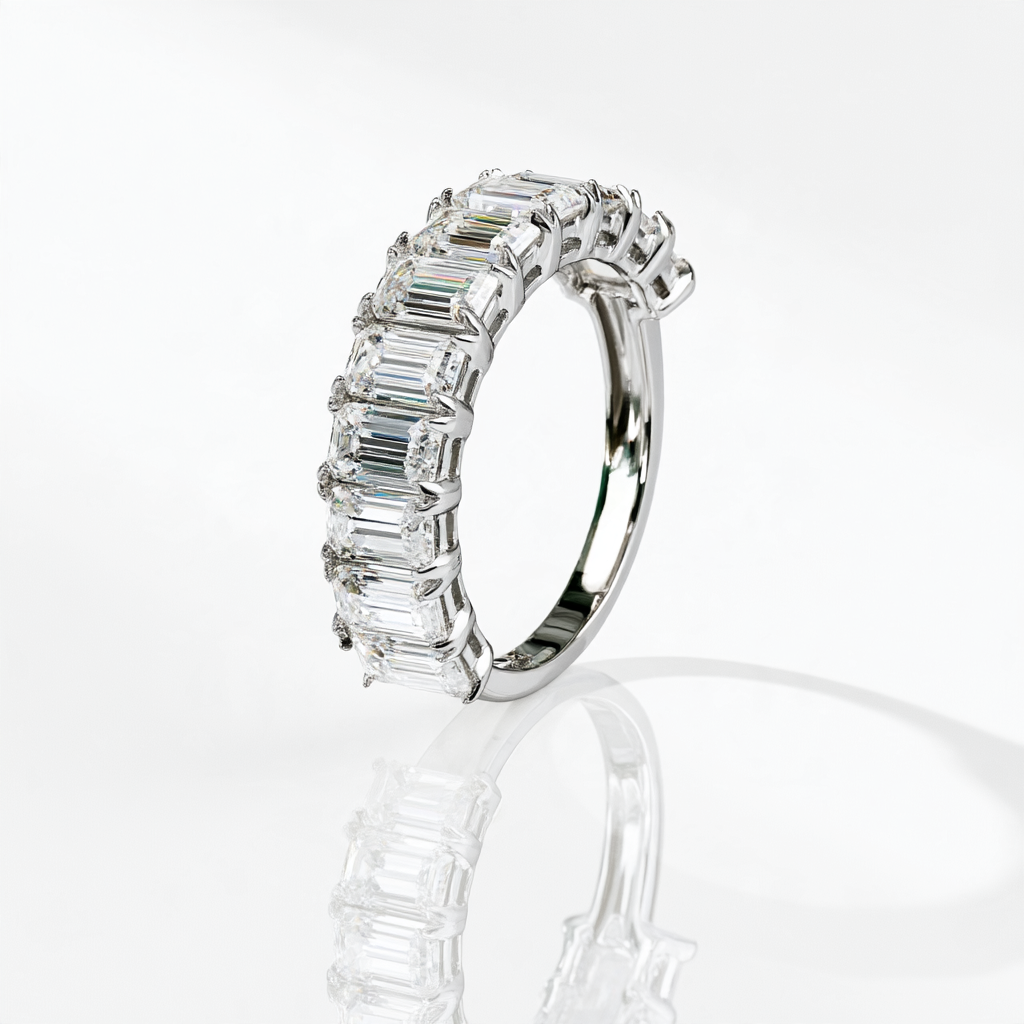 Emerald-cut moissanite half eternity band in rhodium plated sterling silver, upright side view showing the settings and plain band.